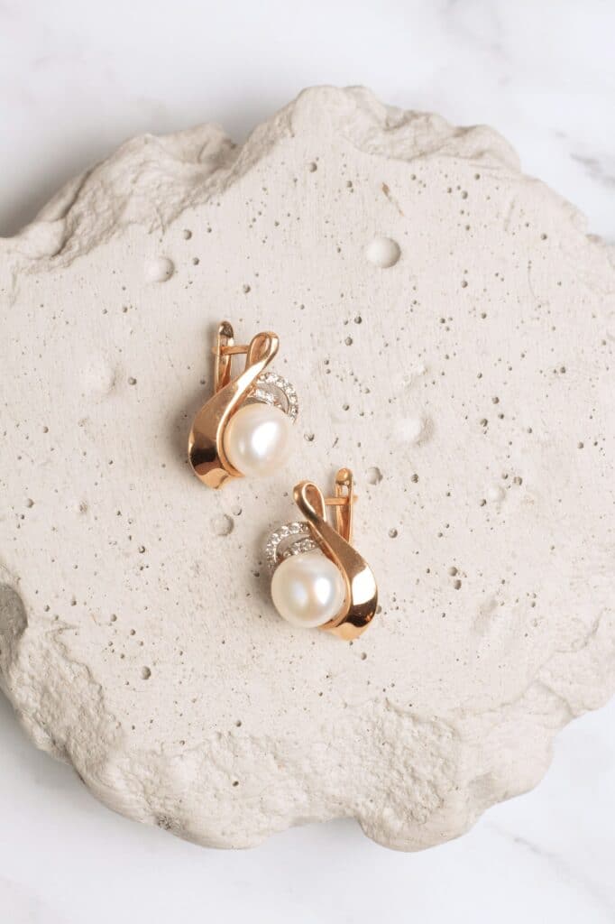 Gold earring with pearl on concrete podium